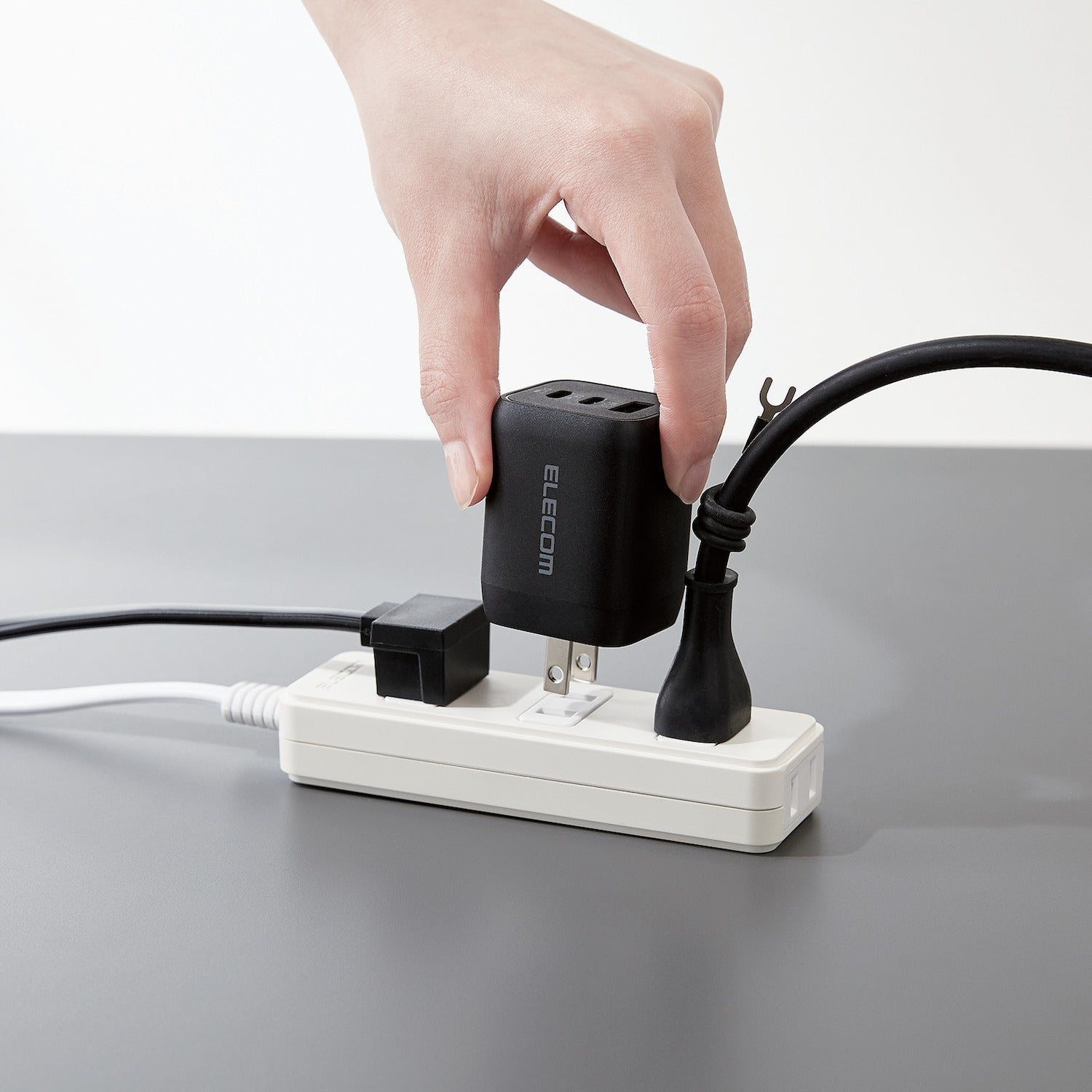Black Compact Charger GaNII 65W hand plugging the charger into a switch | Elecom ultra-high output device charger