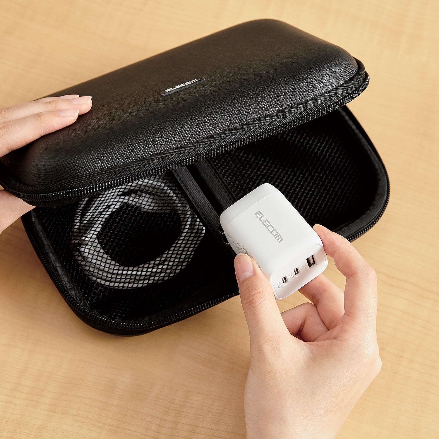 Black Compact Charger GaNII 65W hands placing charger into storage bag | Elecom ultra-high output device charger