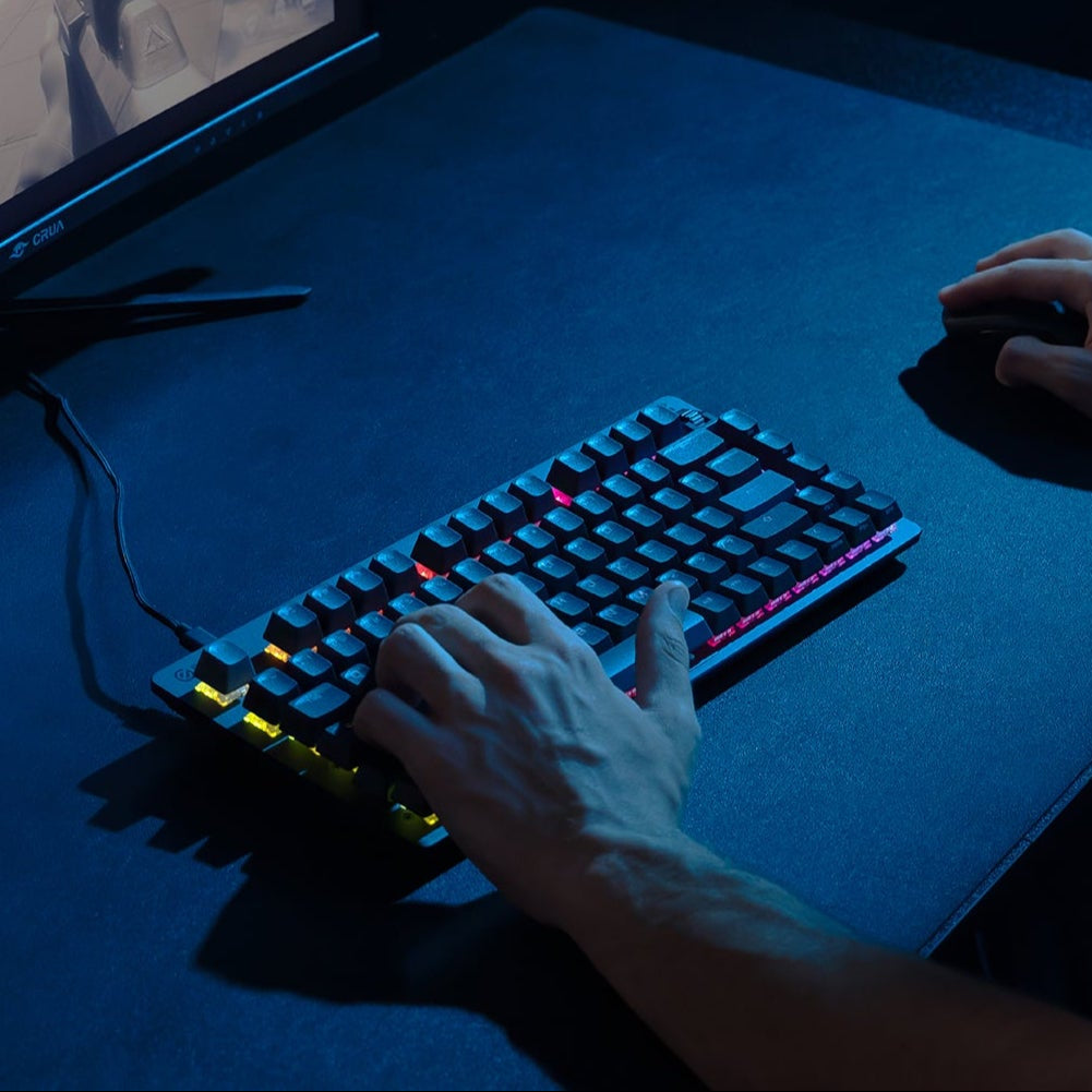 person with hang on keyboard playing a shooting game on computer monitor