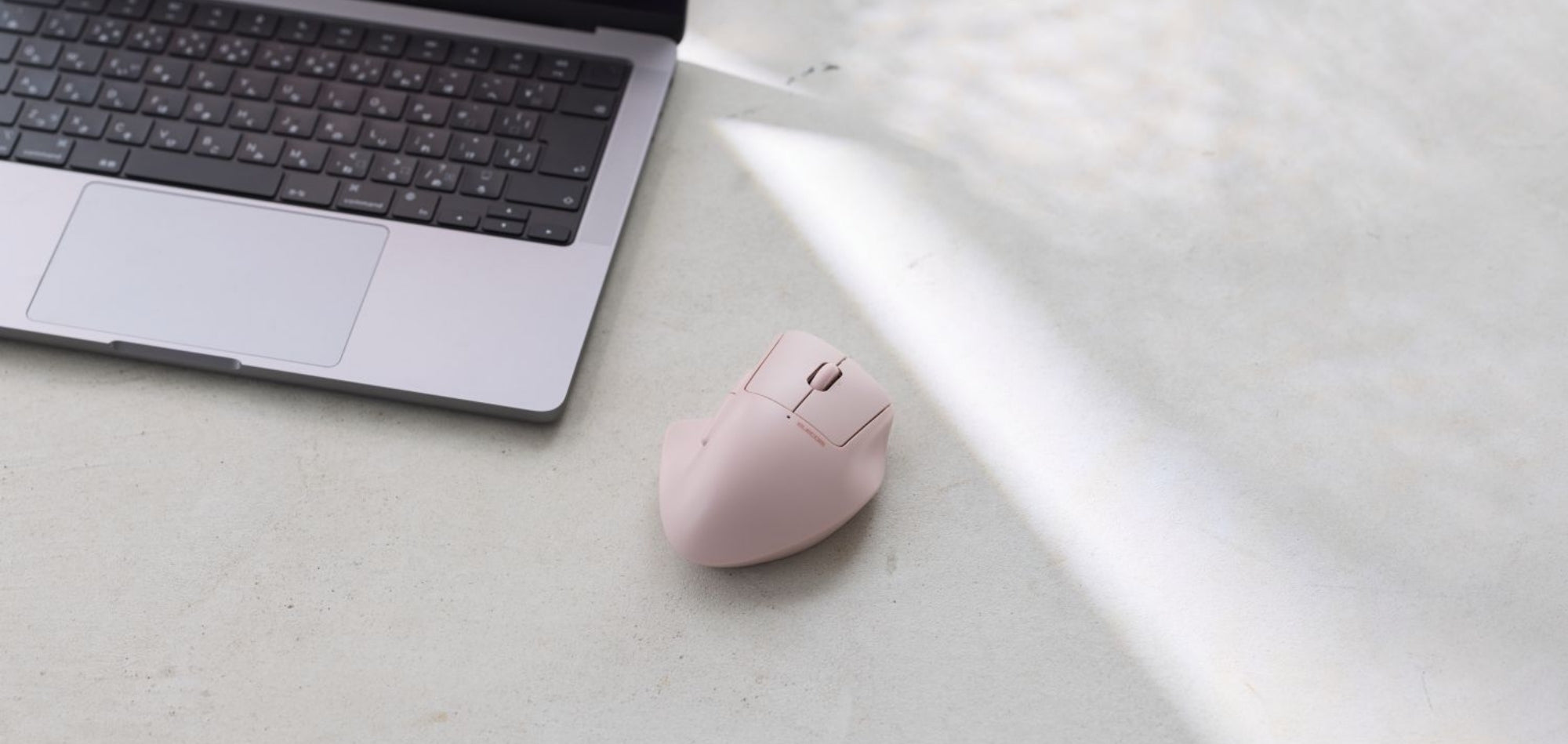 The SH30 Ergonomic Mouse - Bluetooth Version in Pink sitting next to Macbook Laptop