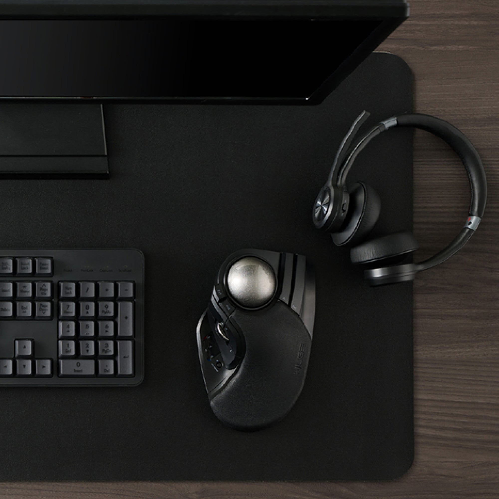 HUGE PLUS trackball mouse placed beside keyboard and headset on dark desk