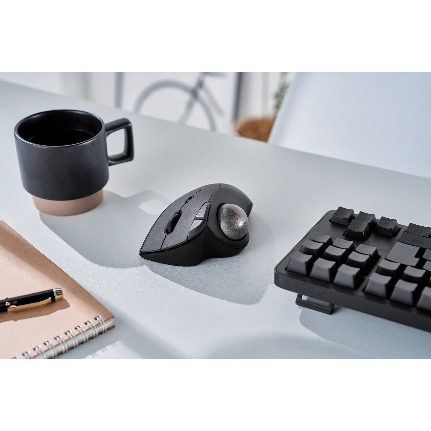 top view black ergonomic trackball mouse with silver ball | trackball mouse with programmable buttons | lifestyle image with black coffee cup and black keyboard on white desk