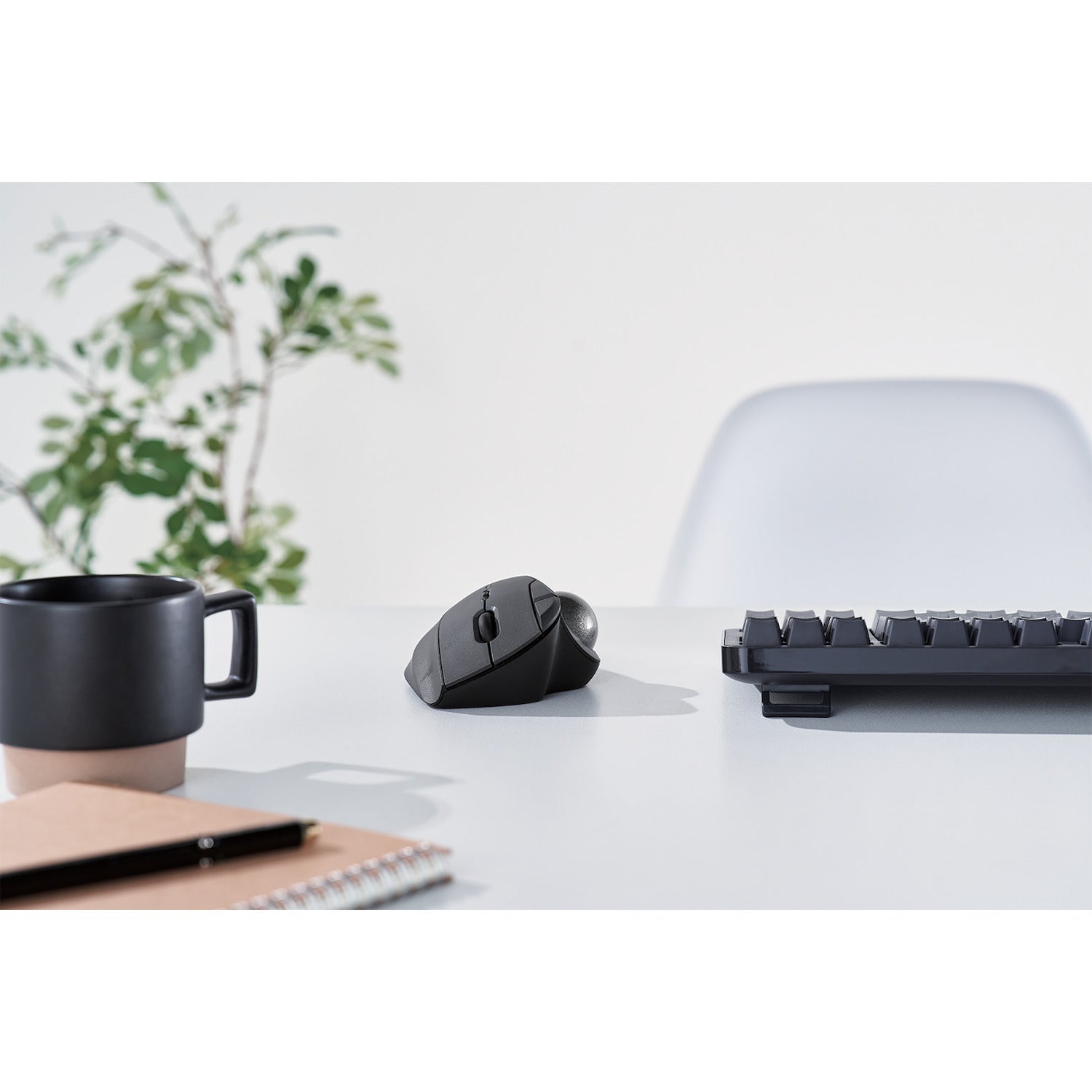 front view black ergonomic trackball mouse with silver ball | trackball mouse with programmable buttons | lifestyle image with black coffee cup and black keyboard on white desk