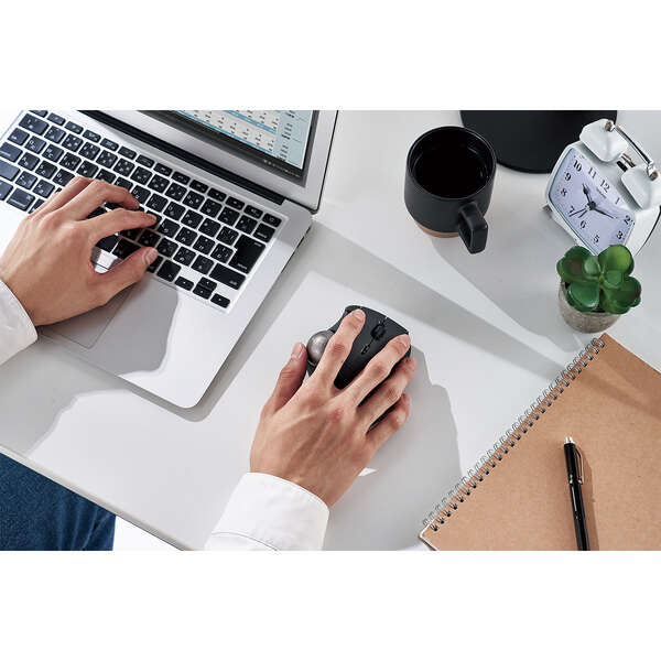 Bluetooth trackball mouse being used with a silver laptop | black and silver trackball can be used with PC or Mac