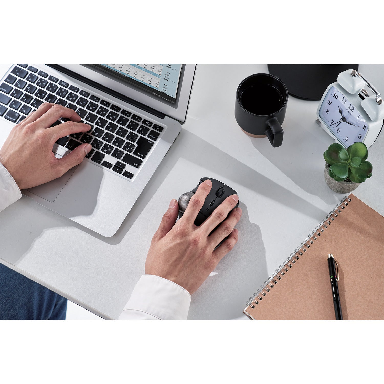 top view person using black ergonomic trackball mouse with silver ball | trackball mouse with programmable buttons | lifestyle image with black coffee cup and black keyboard on white desk with mac computer