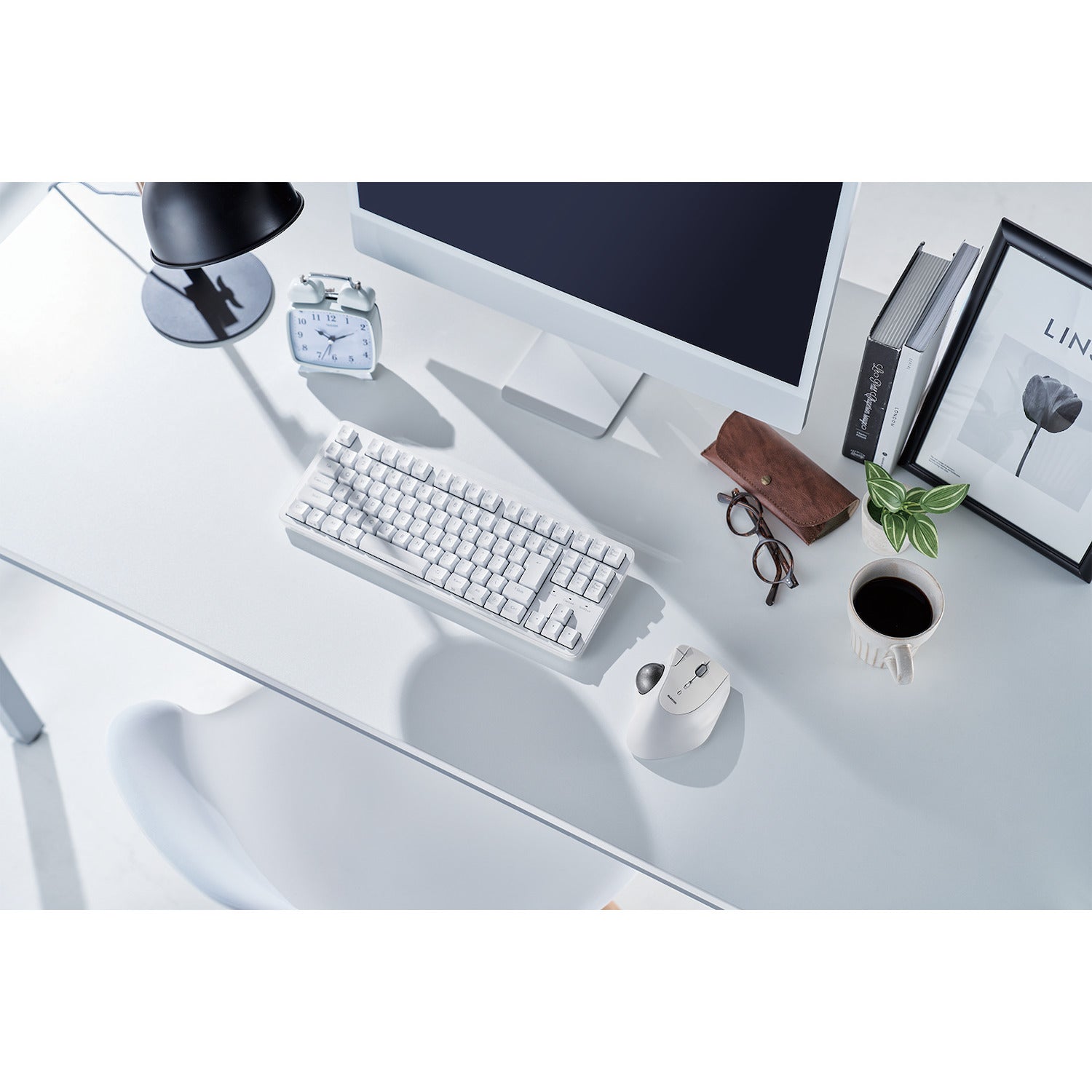 lifestyle image of white and silver ergonomic trackball mouse on white and black decorated desktop