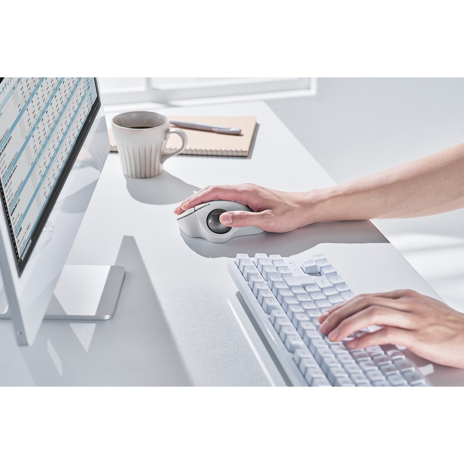 side view of white trackball mouse in use with white monitor and keyboard on white desk | thumb controlled trackball used to alleviate wrist pain