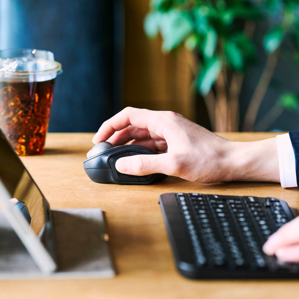 Closeup of someone using bitra index trackball in an office setting with a blurred background.